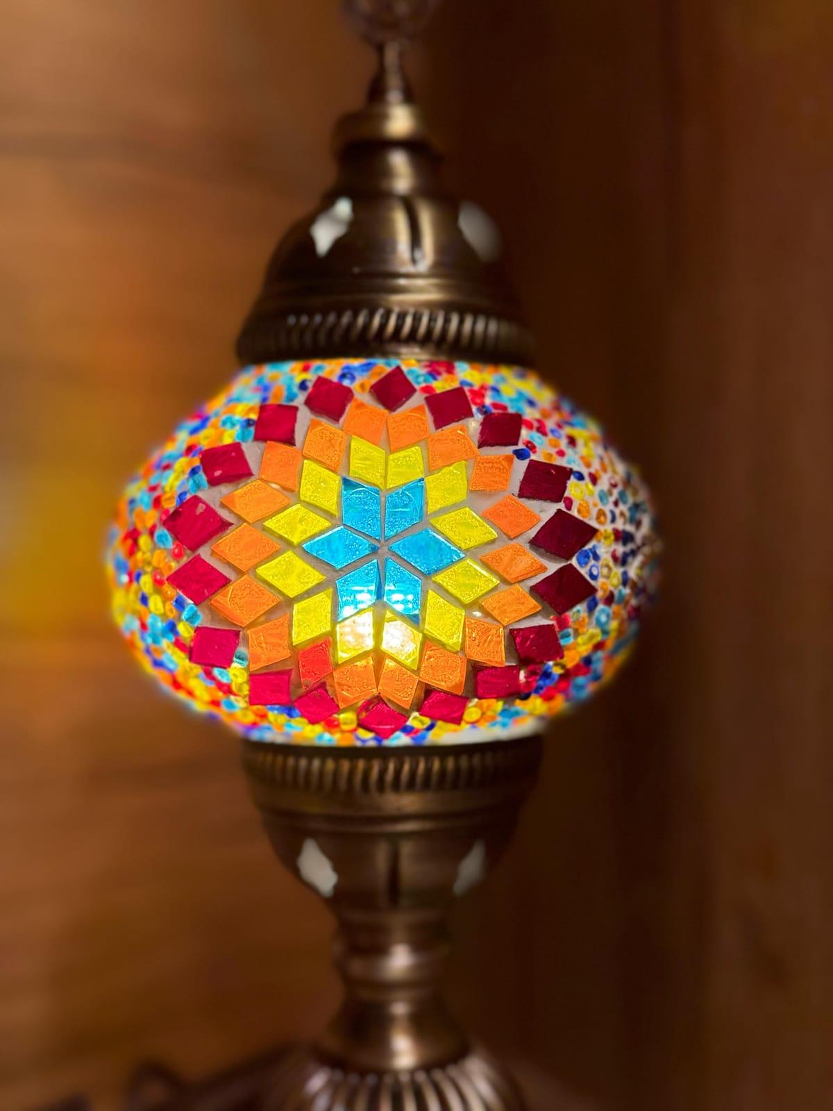 Close-up of a handcrafted Turkish mosaic lamp glowing warm amber and orange